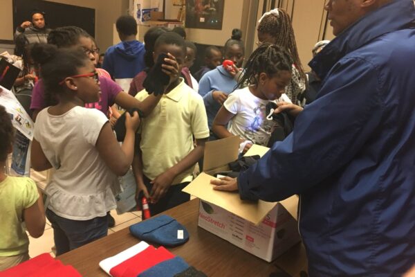 Here, MGG volunteers hand out gloves and scarves while educating about asthma and dental health at "Science and Scarves".